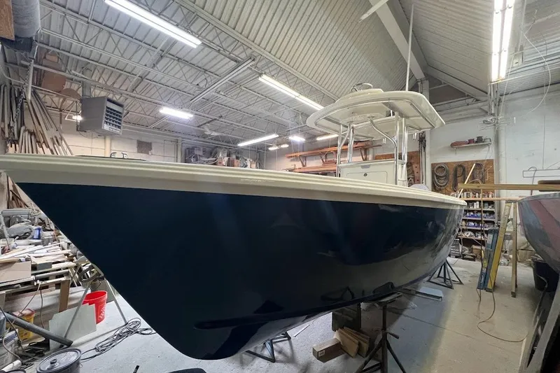 Slide: The Image of Custom Dominion 23 boat, 2023 model, in a workshop setting with tools and equipment. - 14