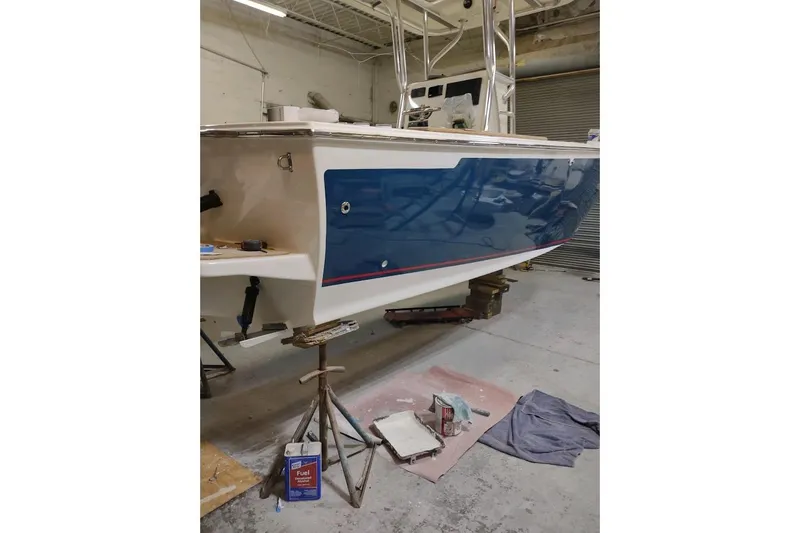 Slide: The Image of Custom Dominion 23 boat, 2023 model, with blue hull in a workshop setting. - 15