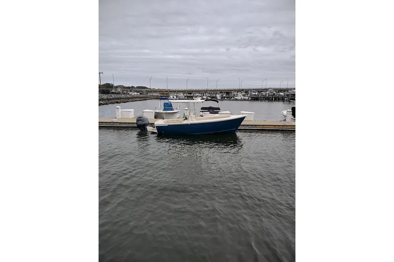 Slide: The Image of Custom Dominion 23 boat docked with American flag, 2023 model, near industrial port. - 16