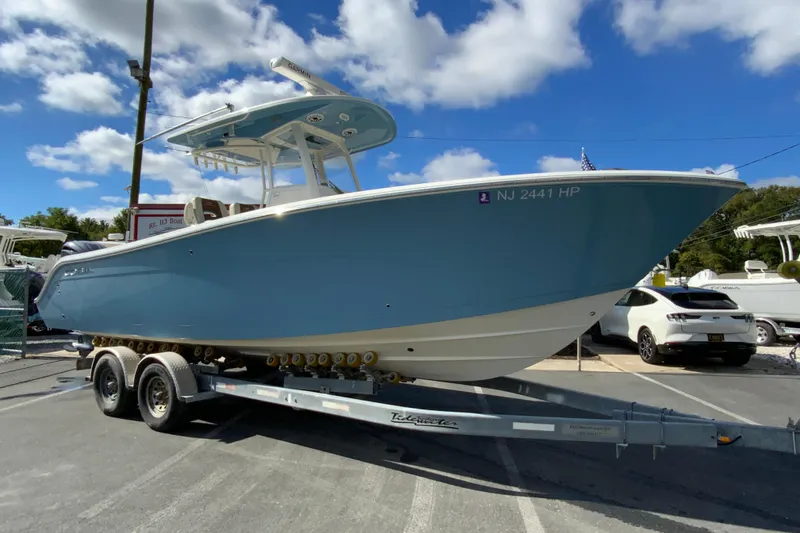 Slide: The Image of 2021 Cobia 280 Center Console boat on trailer under blue sky. - 2
