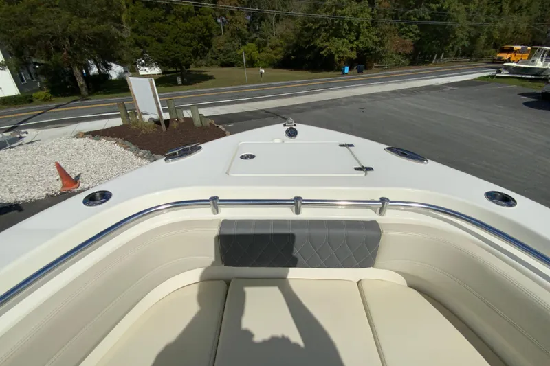 Slide: The Image of 2021 Cobia 280 Center Console boat bow with seating and storage, parked outdoors. - 24