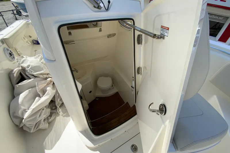 Slide: The Image of 2021 Cobia 280 Center Console boat interior with open door to compact bathroom. - 27