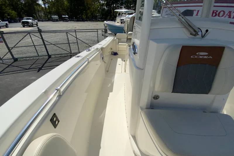 Slide: The Image of 2021 Cobia 280 Center Console boat interior with seating and railing, parked outdoors. - 29