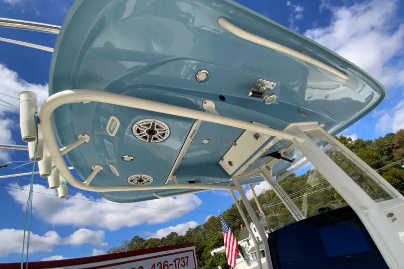 Slide: The Image of 2021 Cobia 280 Center Console boat with blue hardtop and speakers, under a clear sky. - 30