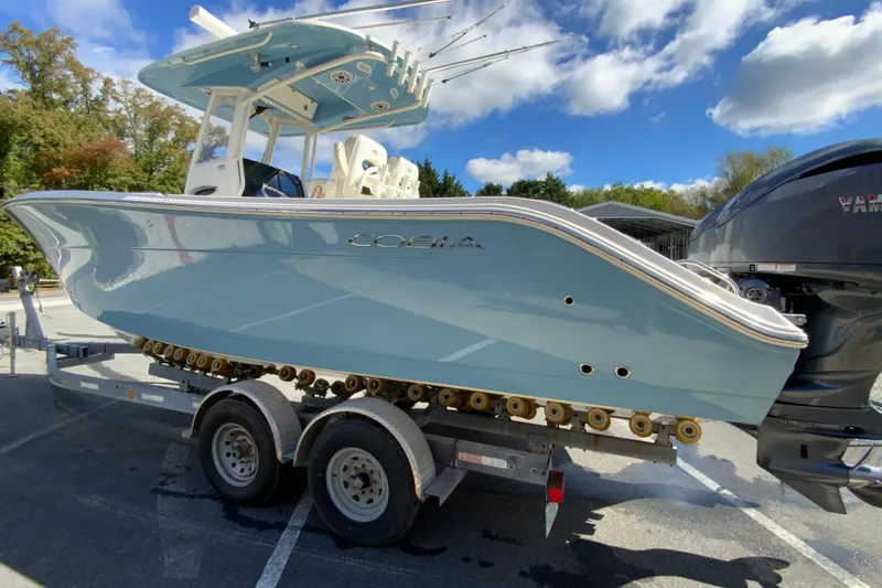 Slide: The Image of 2021 Cobia 280 Center Console boat on trailer under blue sky. - 7