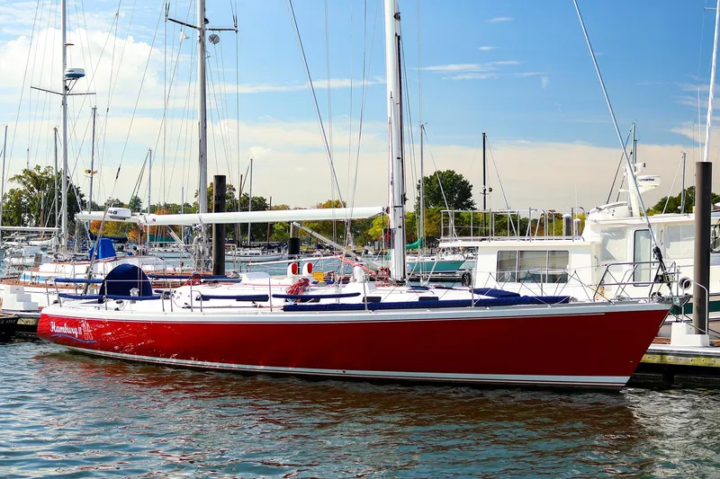 The Image of Red 2002 J Boats J/46 sailboat docked in a marina under a clear blue sky. - 0