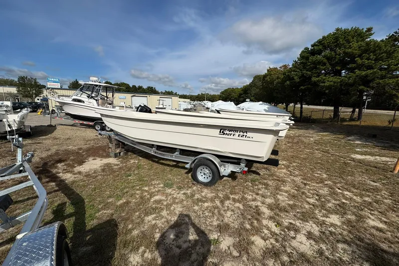 Slide: The Image of 2025 Carolina Skiff E21 DLX Kit boat on trailer, outdoor dealership setting. - 11