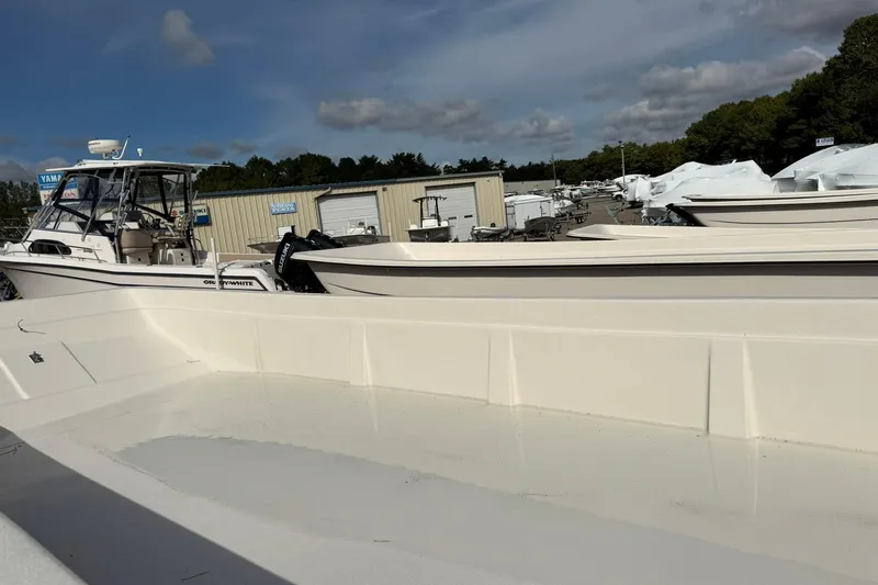 Slide: The Image of 2025 Carolina Skiff E21 DLX Kit boat in a marina with other vessels. - 15