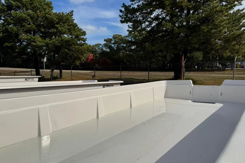 Slide: The Image of 2025 Carolina Skiff E21 DLX Kit boat, empty interior, outdoors, surrounded by trees and fence. - 16