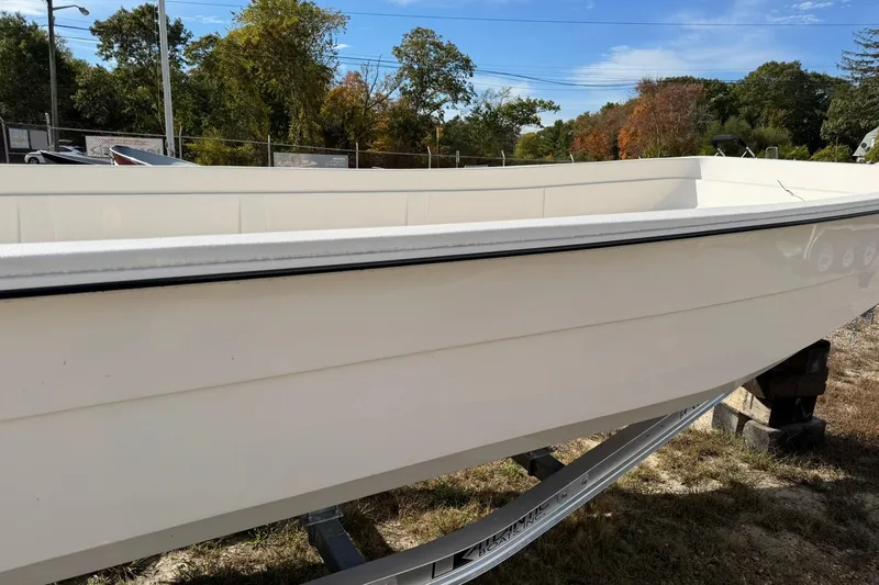 Slide: The Image of 2025 Carolina Skiff E21 DLX Kit boat on trailer, outdoors with trees in background. - 2