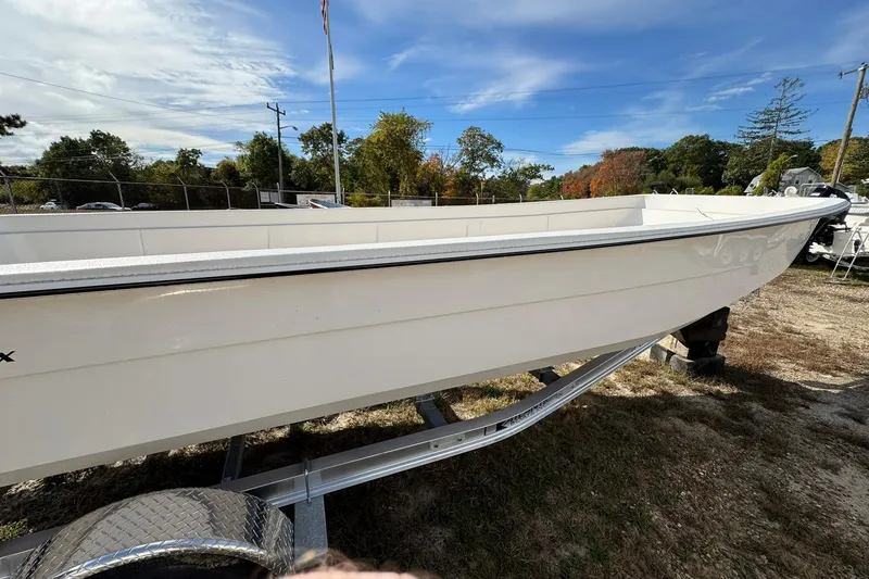 Slide: The Image of 2025 Carolina Skiff E21 DLX Kit boat on trailer, outdoors under blue sky. - 3