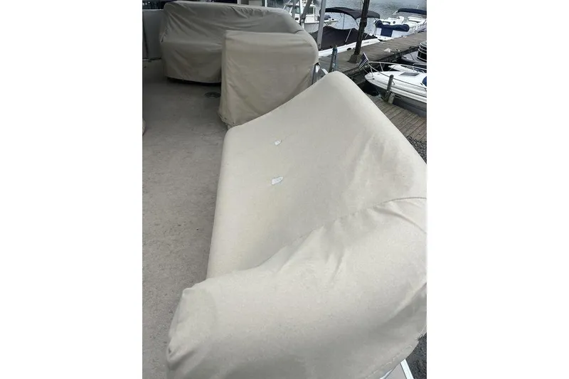 Slide: The Image of Covered seating on a 2016 Godfrey 2086 boat, docked near other vessels. - 12