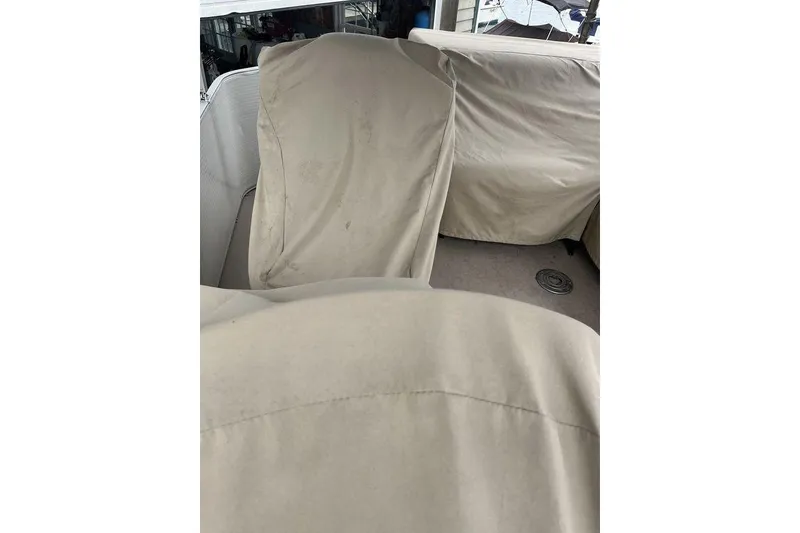 Slide: The Image of Covered seating area on a 2016 Godfrey 2086 boat, featuring beige protective covers. - 13
