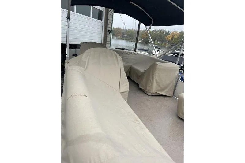Slide: The Image of Covered seating area on a 2016 Godfrey 2086 boat, docked near a lake. - 18