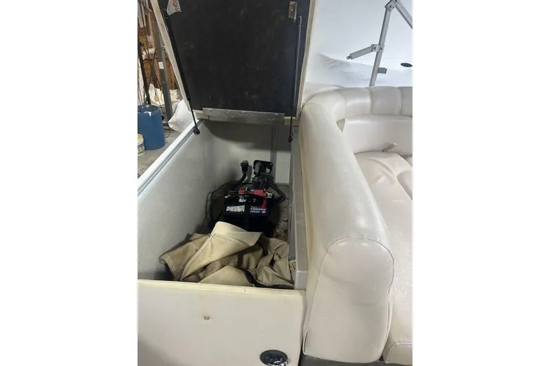 Slide: The Image of Open storage compartment in 2016 Godfrey 2086 boat, revealing battery and beige fabric. - 27