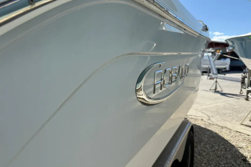 Slide: The Image of 2019 Robalo R242 Center Console boat side view with logo, parked outdoors. - 23