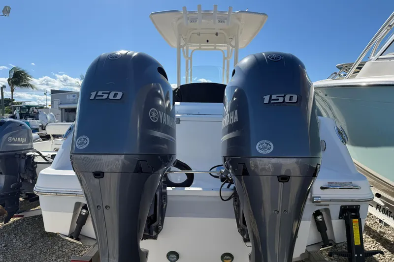 Slide: The Image of 2019 Robalo R242 Center Console with twin Yamaha 150 engines, docked under clear skies. - 24