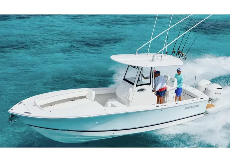 Slide: The Image of 2026 Regulator 25 boat with T-top, docked near a warehouse under a blue sky. - 2