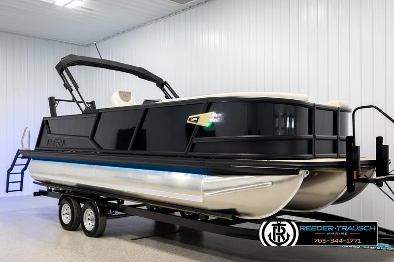 Slide: The Image of 2026 Alera M23L pontoon boat on trailer in indoor showroom. - 2