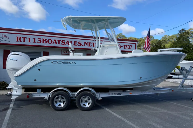 The Image of 2026 Cobia 220 Center Console boat on trailer at dealership. - 1