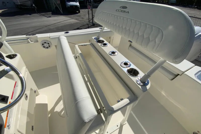 Slide: The Image of 2026 Cobia 220 Center Console boat interior with white seating and rod holders. - 15