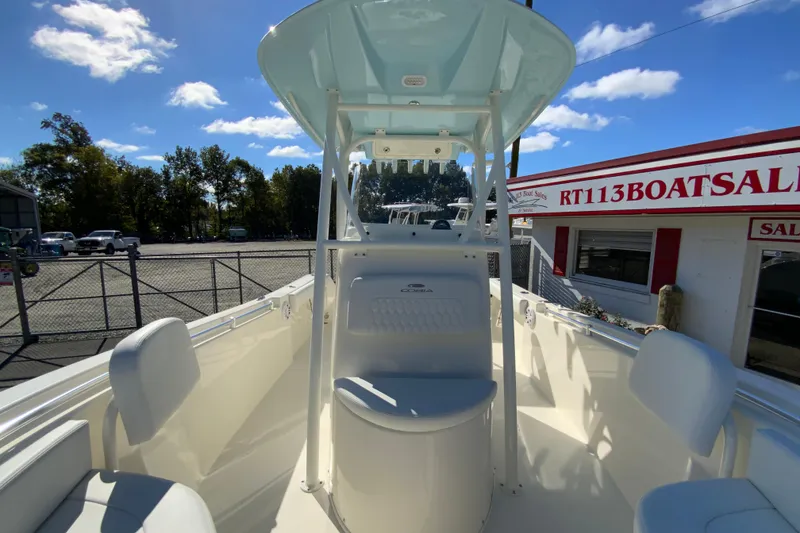 Slide: The Image of 2026 Cobia 220 Center Console boat at dealership under clear blue sky. - 27