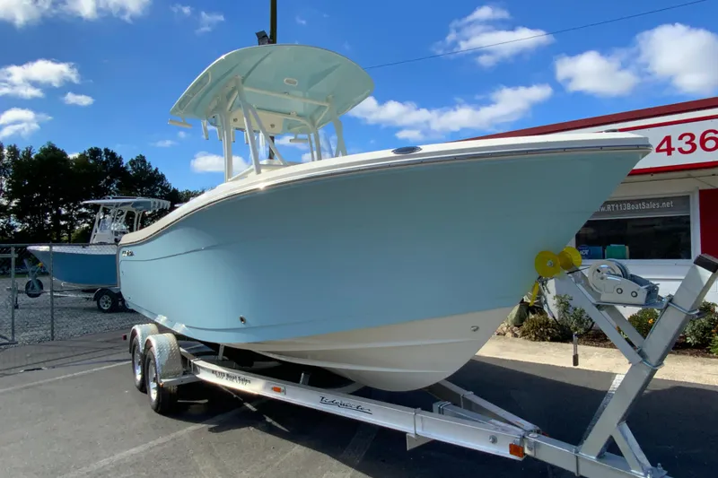 Slide: The Image of 2026 Cobia 220 Center Console boat on trailer, displayed outdoors under blue sky. - 3