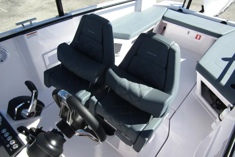 Slide: The Image of 2024 Axopar 25 Cross Top boat interior with dual seats and steering wheel. - 11
