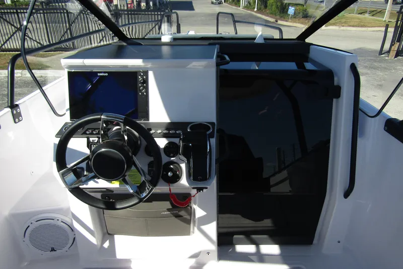 Slide: The Image of 2024 Axopar 25 Cross Top boat cockpit with steering wheel and navigation display. - 12