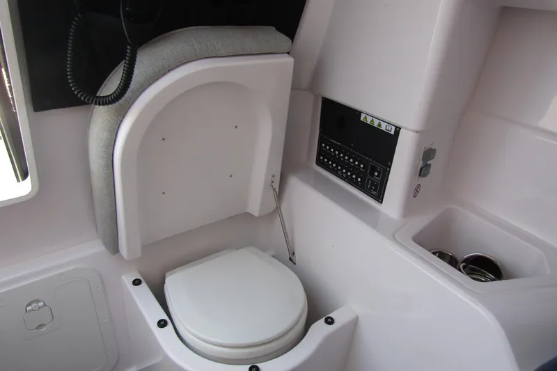 Slide: The Image of 2024 Axopar 25 Cross Top boat interior with compact toilet and control panel. - 23