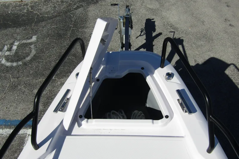 Slide: The Image of 2024 Axopar 25 Cross Top boat bow storage compartment open, showing interior. - 8