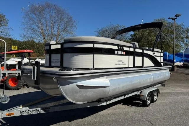 Slide: The Image of 2023 Bennington 22SX pontoon boat on trailer, parked outdoors. - 1