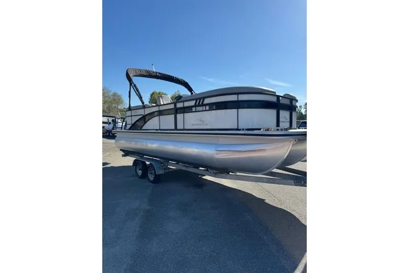 Slide: The Image of 2023 Bennington 22SX pontoon boat on trailer under clear blue sky. - 4
