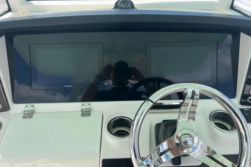 Slide: The Image of 2020 Robalo R302 Center Console helm with dual Garmin displays and chrome steering wheel. - 13