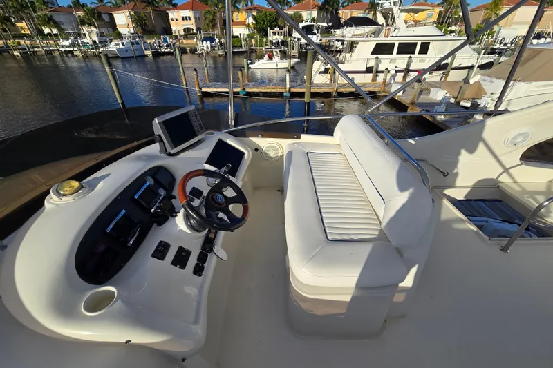 Slide: The Image of Flybridge of 1997 Sunseeker Manhattan 48 yacht with helm controls and seating, docked at marina. - 17