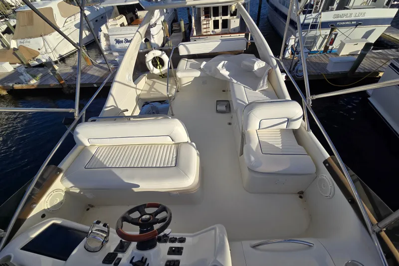 Slide: The Image of 1997 Sunseeker Manhattan 48 yacht interior with white seating and steering wheel, docked at marina. - 21