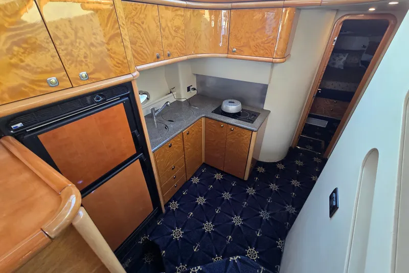 Slide: The Image of Interior of 1997 Sunseeker Manhattan 48 yacht kitchen with wood cabinets and nautical carpet. - 56