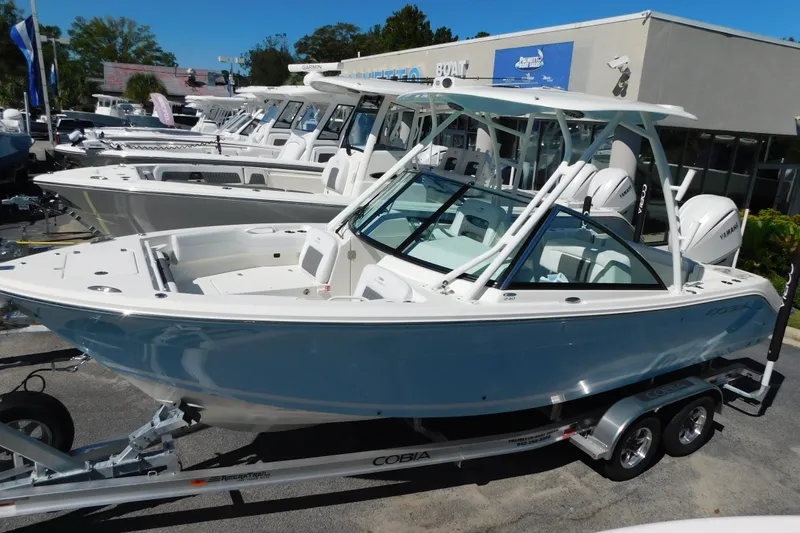 The Image of 2026 Cobia 240 Dual Console boat on trailer, displayed at dealership. - 0