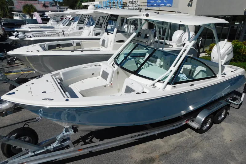 Slide: The Image of 2026 Cobia 240 Dual Console boat on trailer with Yamaha engine, parked outdoors. - 2