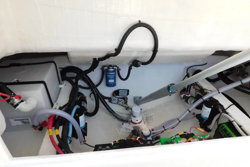 Slide: The Image of 2026 Cobia 240 Dual Console boat storage compartment with visible wiring and components. - 55