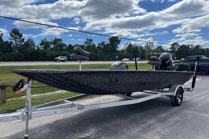 Slide: The Image of 2026 Xpress XP200 boat on trailer, camo design, parked outdoors under cloudy sky. - 4