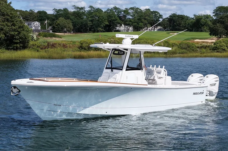 The Image of 2025 Regulator 31 boat cruising on a scenic lake with lush greenery. - 0