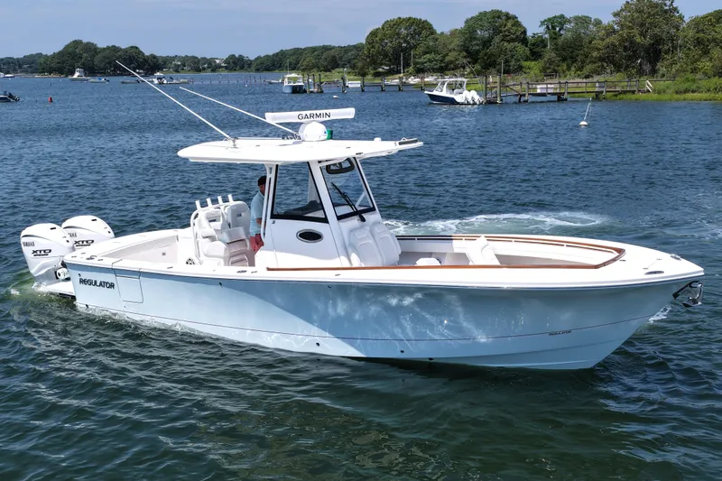 Slide: The Image of 2025 Regulator 31 boat cruising on a scenic lake with lush greenery. - 11