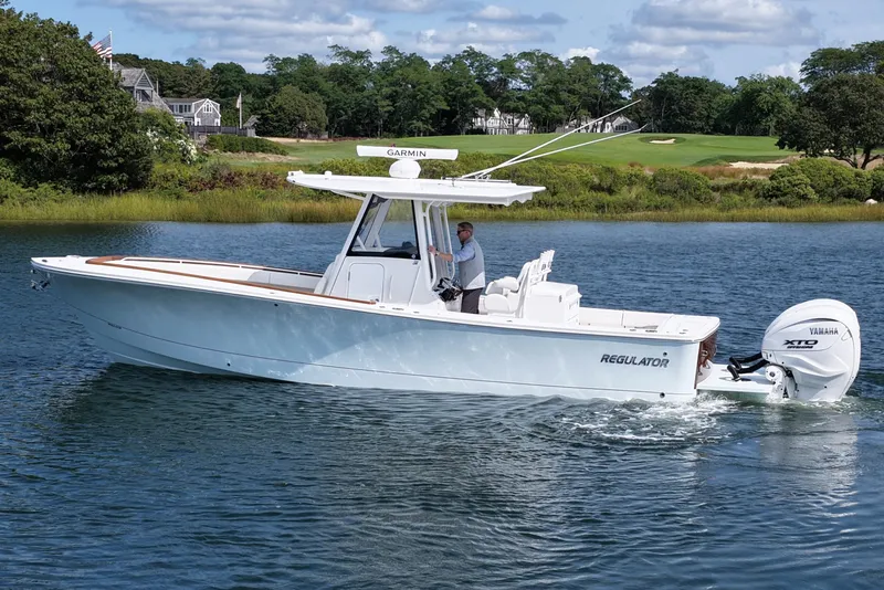 Slide: The Image of 2025 Regulator 31 boat cruising on a scenic lake with lush greenery. - 9