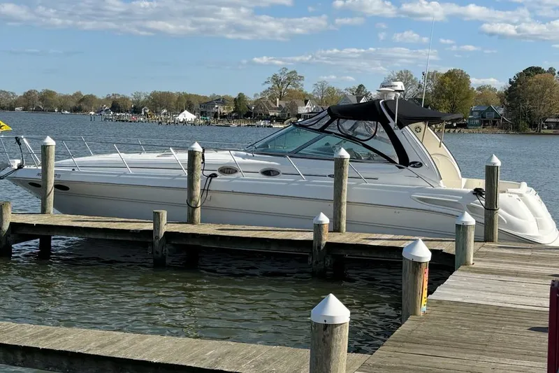 The Image of 2001 Sea Ray 410 Sundancer yacht docked at a serene marina with clear skies. - 0