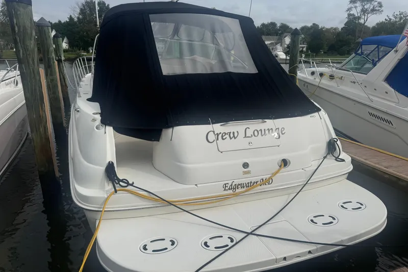 Slide: The Image of 2001 Sea Ray 410 Sundancer docked, featuring "Crew Lounge" name and black cover. - 2