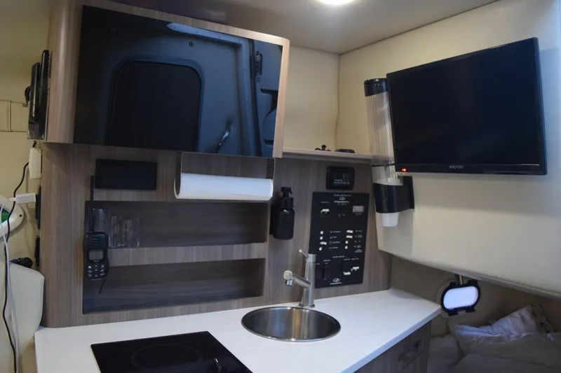 Slide: The Image of 2021 Regal 26 XO boat interior with kitchenette, sink, and mounted TV. - 124