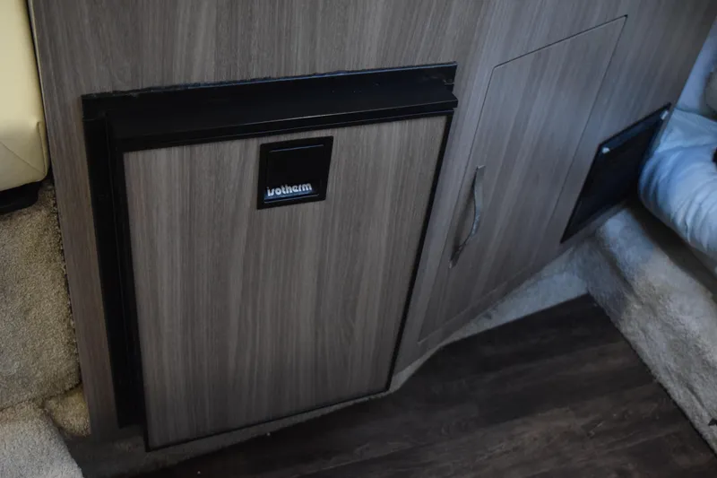 Slide: The Image of 2021 Regal 26 XO interior with wood paneling and compact refrigerator. - 126