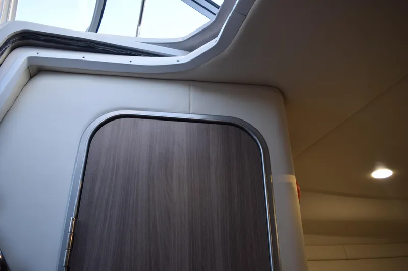 Slide: The Image of Interior view of 2021 Regal 26 XO boat cabin with wooden door and ceiling light. - 138