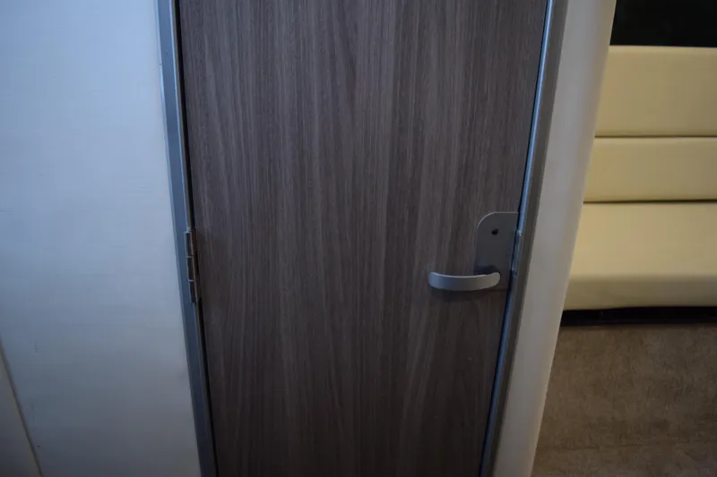 Slide: The Image of Interior cabin door of 2021 Regal 26 XO boat, featuring wood finish and modern handle. - 140